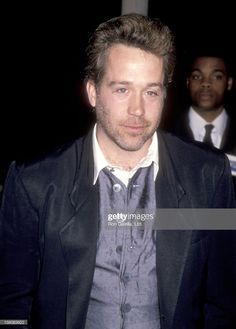 a man wearing a suit and tie standing next to another man in front of him