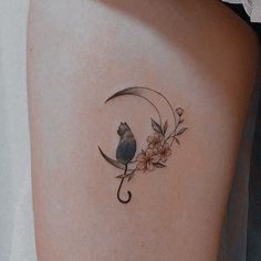 a small bird sitting on the moon with flowers around it's back side tattoo