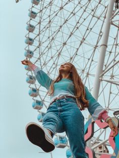 a woman is doing tricks on a skateboard in front of a large ferris wheel