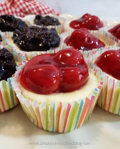 several cupcakes with cherries and blueberries on them