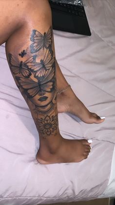 a woman's legs with flowers and butterflies tattooed on the bottom part of her leg