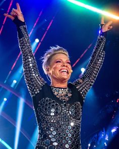 a woman with her arms up in the air on stage at a concert or show