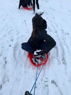 two people riding sleds down a snow covered slope with one person on it