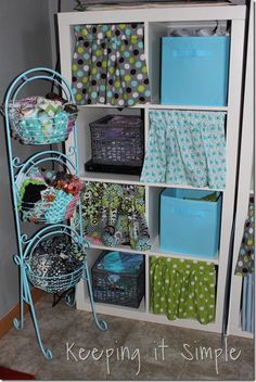 a white bookcase filled with lots of different types of fabric and boxes on top of it