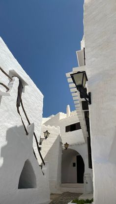 an alley way with white buildings on both sides and a street light in the middle