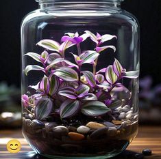 a glass jar filled with purple flowers and rocks next to a smiley face sticker