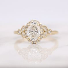 a yellow gold engagement ring with an oval cut diamond surrounded by small round brilliant diamonds