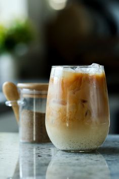 an iced drink in a glass next to a wooden spoon on a marble counter top