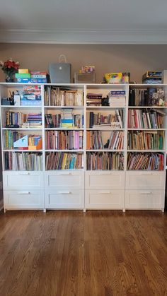 a bookcase filled with lots of books on top of wooden floors in a room