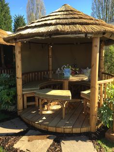 a wooden gazebo sitting on top of a lush green field