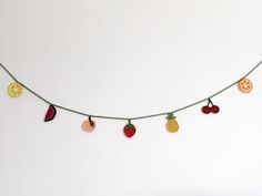 an orange, strawberry and lemon slice garland is hanging from a string on a white wall