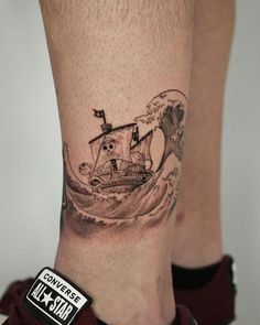 a man's foot with a tattoo on it and an image of a boat in the water