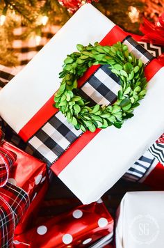 presents wrapped in red, white and black wrapping paper with a wreath on top sitting next to each other