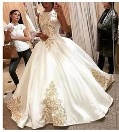 a woman in a white and gold wedding dress taking a selfie with her cell phone