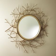 a mirror mounted to the side of a wall next to a tree branch decoration on it