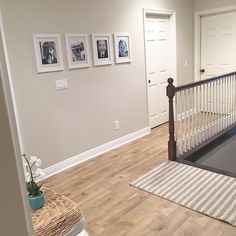 an empty room with pictures on the wall and wooden stairs leading up to it's second floor