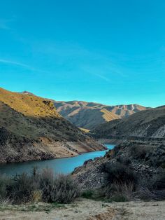 there is a river in the middle of some hills and grass on both sides of it