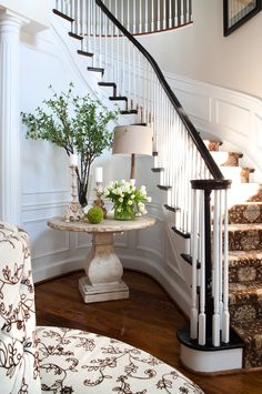 there is a vase with flowers on the table next to the stairs