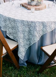 a table with two chairs and a lace tablecloth on it