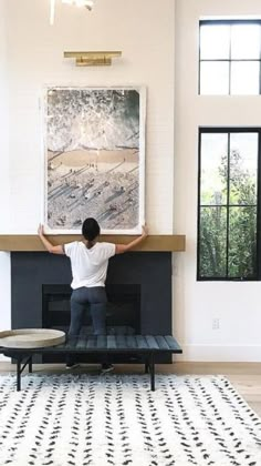 a man standing in front of a fireplace with his hands on the mantle