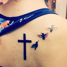 a woman with a tattoo on her back has a cross and two hummings painted on it