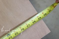 a person measuring the width of a piece of wood with a yellow tape on it