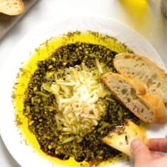 a person holding a piece of bread over a bowl of food