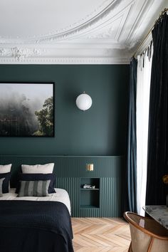 a bedroom with green walls and white trim on the ceiling, along with a large bed