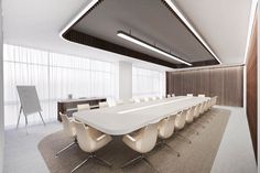 an empty conference room with white chairs and a long table in front of a projector screen