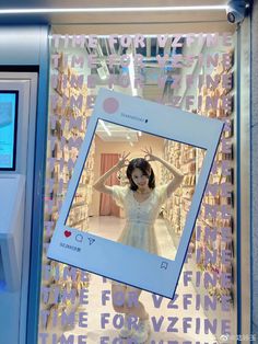 a woman standing in front of a store window with her hands behind her head and wearing a white dress