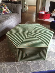 a green box sitting on top of a rug in front of a couch and fireplace