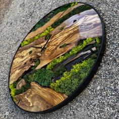 a clock made out of wood with moss growing on it's sides and trees in the middle