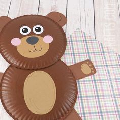 a paper plate shaped like a bear on a wooden floor with plaid tablecloths