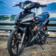 a black motorcycle parked on top of a dirt field next to a cityscape