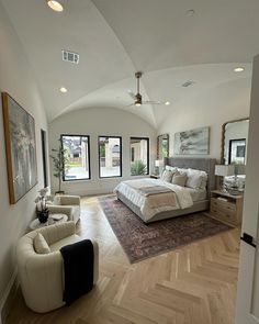 a large bedroom with two white chairs and a big bed in the middle of it