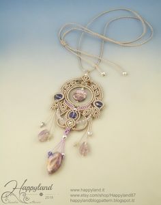 a necklace with an intricate design and beads hanging from it's side on a white surface