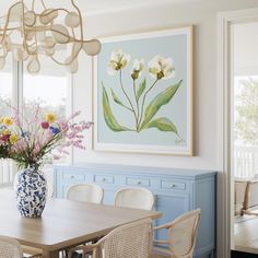 a blue and white vase filled with flowers sitting on top of a wooden dining room table