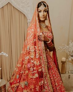 a woman in an orange bridal gown and veil with her hands on her hips