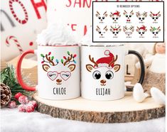 two coffee mugs decorated with reindeer faces and santa's hats on them, sitting next to a christmas decoration