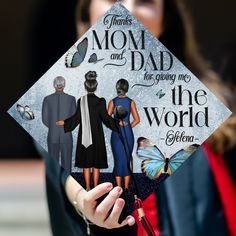 a woman holding up a graduation cap that says, thanks mom and dad for giving me the world shema