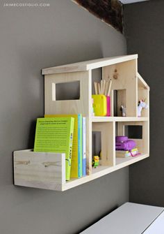 a shelf with books and other items on it in a room that is painted gray