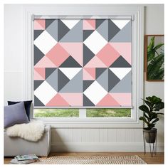 a living room with a large window covered in pink and grey geometric shapes on the blinds