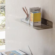 a couple of books are sitting on a shelf next to a magazine rack and window