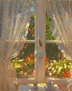 an open window with curtains and flowers outside