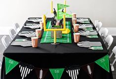 a football themed party table with black and green paper plates, napkins and cups