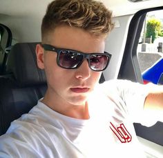 a young man wearing sunglasses sitting in the back seat of a car