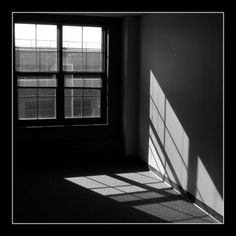 an empty room with the sun shining through the window and casting shadows on the wall