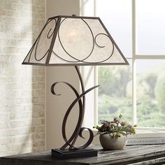 a table lamp sitting on top of a wooden table next to a vase with flowers