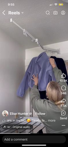 a woman hanging clothes on a rail in a room