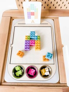 a wooden tray with legos on top of it and a sign above the tray